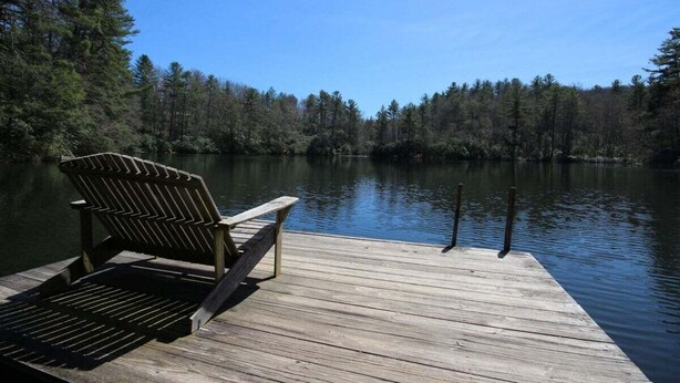 Une jet ée en bois, agrémentée d’un banc et d’un barbecue, d’où l’on peut admirer un lac paisible entouré d’arbres.