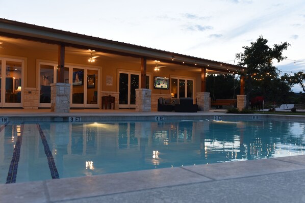 A poolside area with a covered seating area, stone pillars, and a television screen. - Sleeps 33, Private pool & putting green,10 min from Garner State Park, Frio Riv. (Utopia)