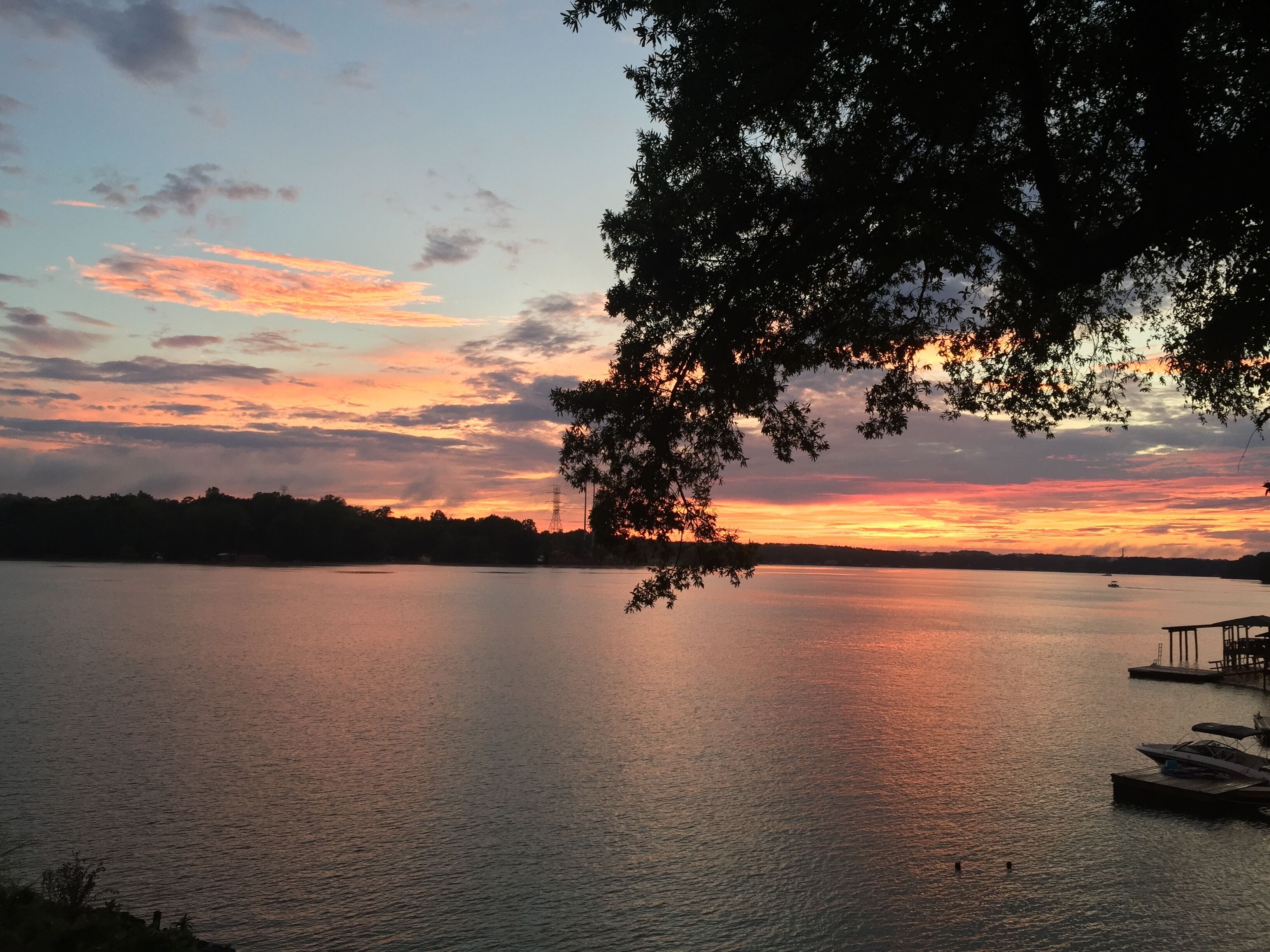 Un lago tranquilo al atardecer con un muelle y un bote.