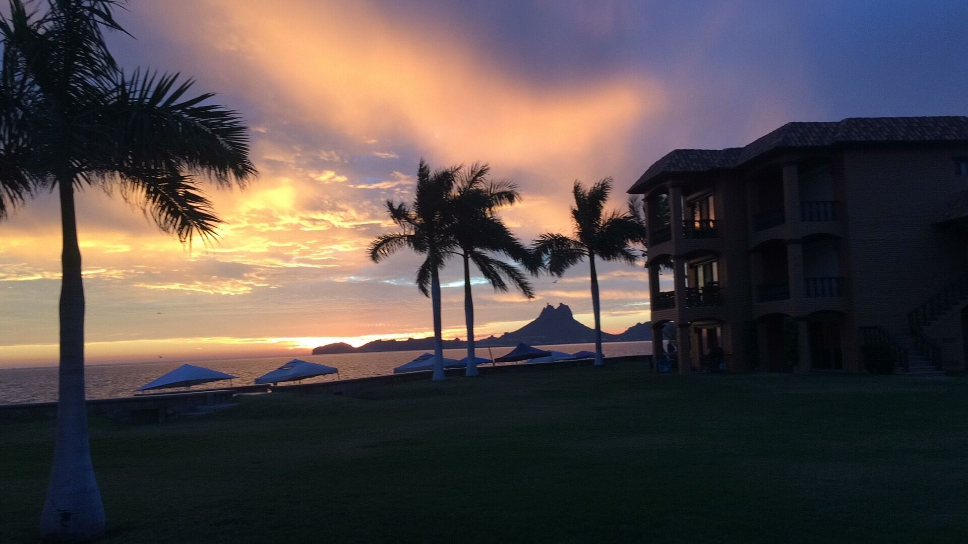 Ein Resort mit Blick auf den Strand, Palmen und einem Gebäude mit Balkonen.