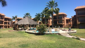 Een resort met meerdere gebouwen, een centraal gelegen zwembad en palmbomen.