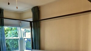 Ein Hotelzimmer mit einem Bett, Kissen, einem Nachttisch, einer Lampe und einem Fenster mit Vorhängen.