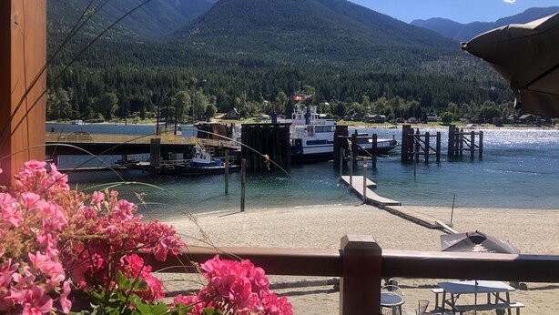 A lakeside dock with boats, a wooden pier, and a mountain backdrop. - Downtown 1BR suite, ground floor, level entry. (Nelson)