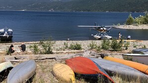 A lakeside scene with a seaplane, boats, and mountains in the background. - Downtown 1BR suite, ground floor, level entry. (Nelson)