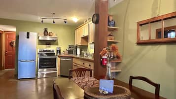 A compact kitchen with a refrigerator, oven, microwave, and a dining table with chairs.