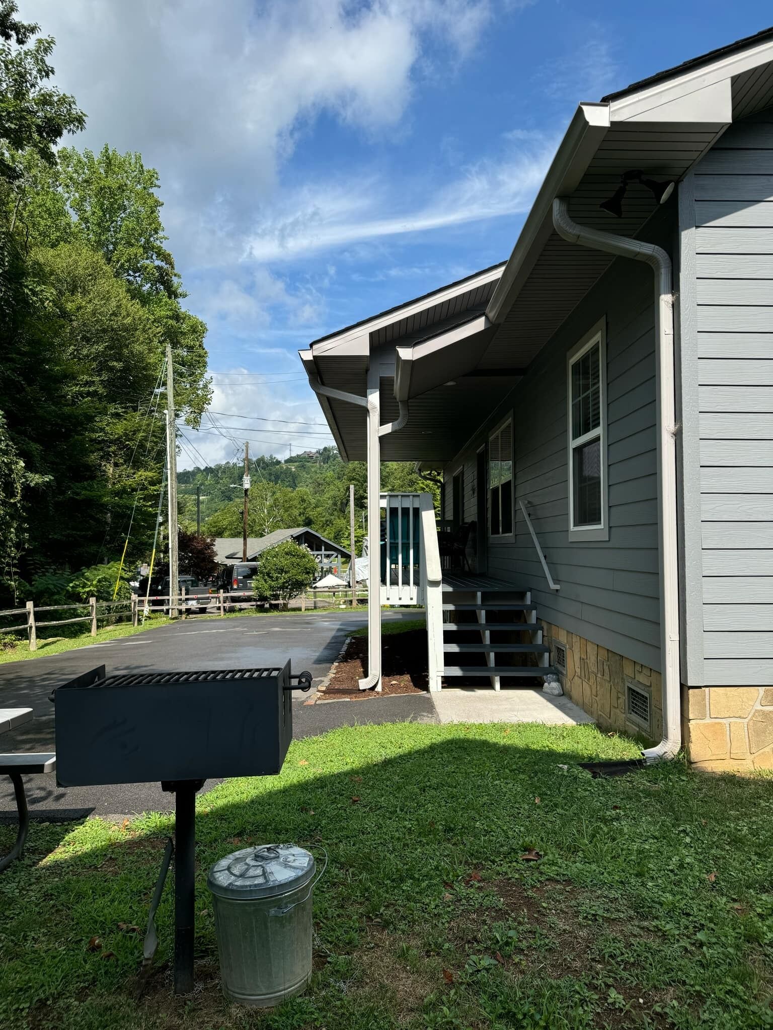 A building with a covered porch, a trash can, and a mailbox.