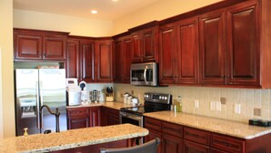 A kitchen with wooden cabinets, granite countertops, stainless steel appliances, and a breakfast bar. - “A Shore Thing “ A Gorgeous Lakefront Home Steps Away From Beaver Lake (Garfield)