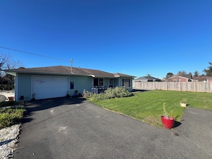 Ein eingeschossiges Haus mit Garage, Veranda und gepflegtem Rasen.