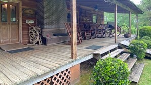 A rustic wooden cabin with a brick fireplace, outdoor seating, and antlers displayed outside.