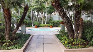 A pool area surrounded by palm trees and greenery, with a clear view of the pool's edge and surrounding plants. - Penthouse - Resort living (Irvine)