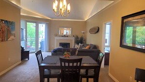 A dining area with a table and chairs, a fireplace, a sofa, and a chandelier. - Penthouse - Resort living (Irvine)