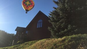 Een luchtballon vliegt boven een huis met een hellend dak en een groot raam.