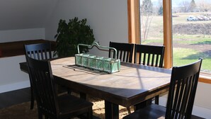 Een eethoek met een houten tafel en vier stoelen, een groene mand en een potplant.