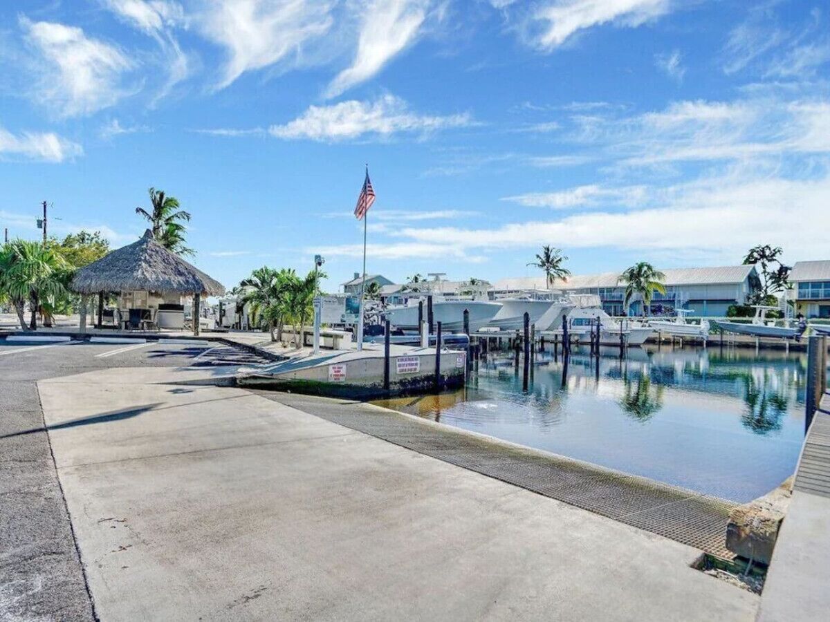 A marina with boats docked, a flagpole with an American flag, and a thatched-roof structure.