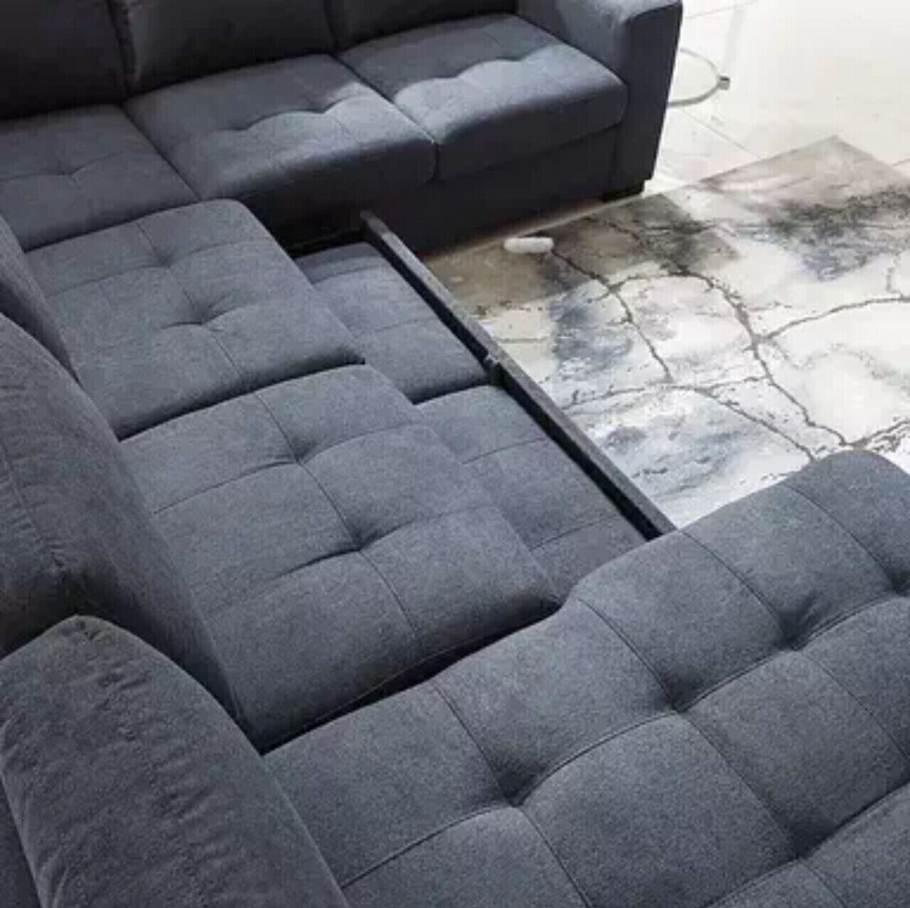 Un canapé modulable au design épuré, un sol en pierre et une vue partielle sur un mur blanc.