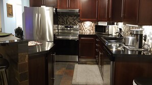 A modern kitchen with dark wooden cabinets, stainless steel appliances, and a tiled backsplash.