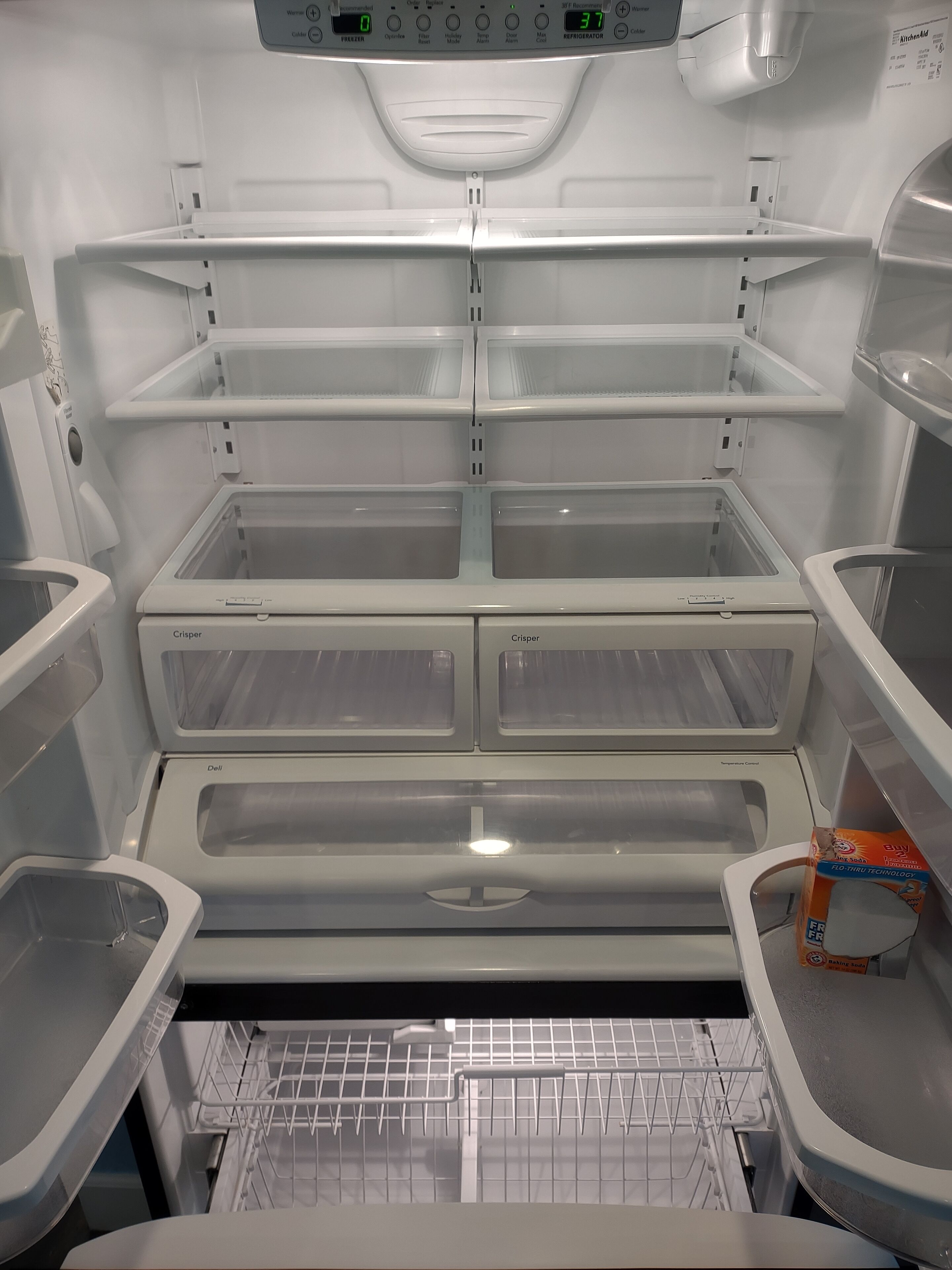 A modern, empty refrigerator with multiple shelves and a freezer compartment.