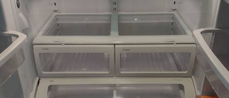 A modern, empty refrigerator with multiple shelves and a freezer compartment.