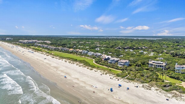 Un complejo turístico costero con propiedades frente a la playa, campo de golf y exuberante vegetación.