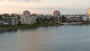 A waterfront hotel with multiple buildings, some with red roofs, and a calm body of water in the foreground.