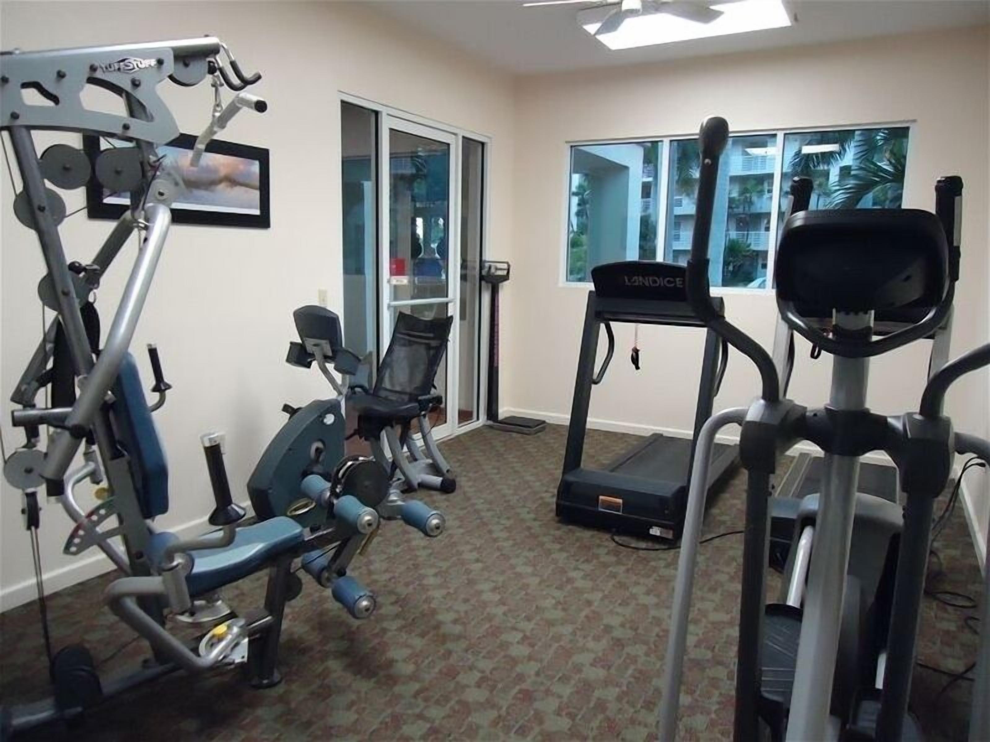 Un gimnasio en casa con diversos equipos de ejercicio, incluyendo una cinta de correr, máquina de pesas y bicicleta estática.