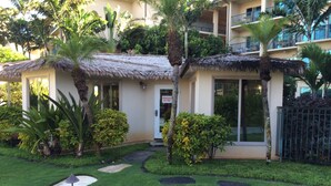 Um hotel com estrutura de telhado de palha, rodeado por jardins bem cuidados e palmeiras.