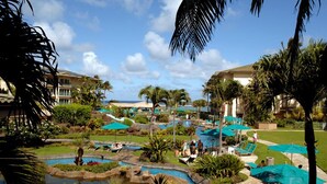 Um resort com área de piscina, palmeiras e céu claro.
