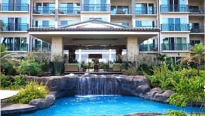 Um hotel com piscina, cachoeira, várias varandas e área coberta.