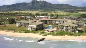 Resort com vários edifícios, praia e montanhas ao fundo.