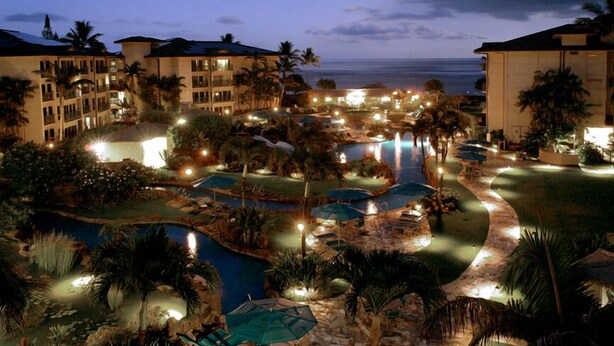 Resort com várias piscinas, palmeiras e vista para a praia.