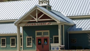 Un edificio con fachada verde y una puerta roja con el rótulo "Julian Library".