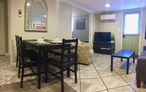 A dining area with a table and chairs, a sofa, a TV, and an air conditioner. - Private, Dog-Friendly Asheville APT. Minutes to *Downtown, River Arts, Biltmore* (Asheville)