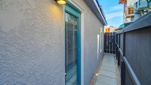 Een smal pad dat leidt naar een huis met een blauwe deur en een lamp erboven.