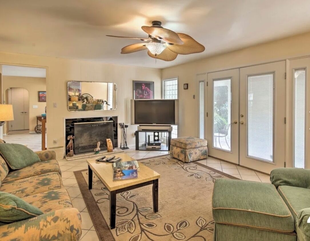 A living room with a fireplace, television, and a ceiling fan.
