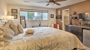Ein Schlafzimmer mit Bett, Deckenventilator, Fenster, Fernseher und einer Küchenzeile.