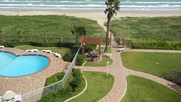 A pool area with a view of the beach and ocean.
