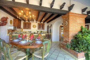 Cozy dining area with a brick fireplace, exposed beams, and a chandelier.