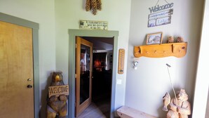 A wooden bear holding a sign, a welcome sign, and a shelf with pinecones and a fishing rod.
