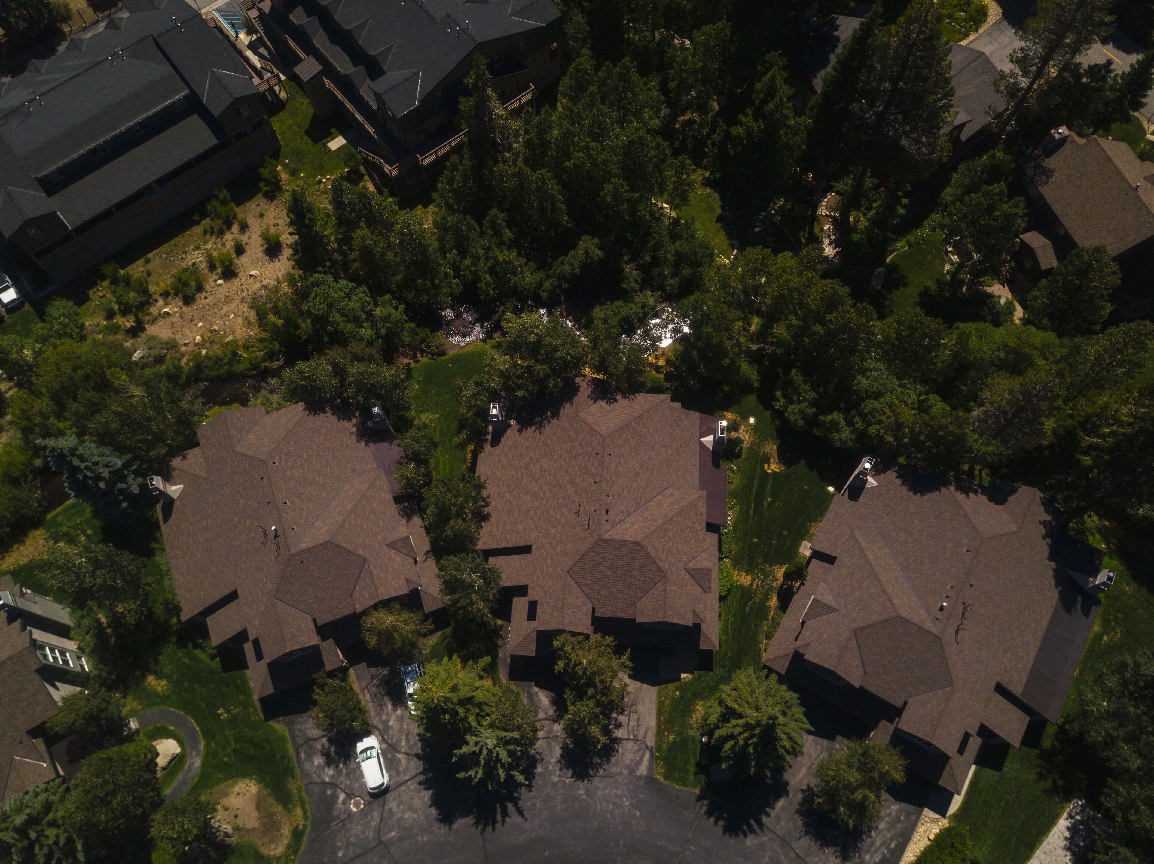 Une vue aérienne d’un quartier résidentiel composé de nombreuses maisons, chacune ayant un style de toit distinct et étant entourée d’arbres.