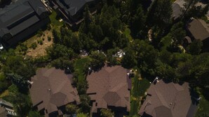 An aerial view of a residential area with multiple houses, each featuring a distinct roof design and surrounded by trees.