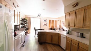A modern kitchen with wooden cabinets, a white refrigerator, and a built-in dishwasher.