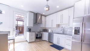 A modern kitchen with white cabinets, stainless steel appliances, and a blue rug. - Fox Den at Fox Hollow (Aldrich)