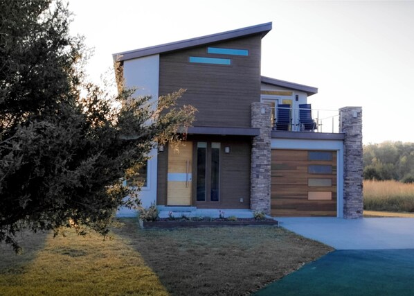 A modern two-story house with a flat roof, large windows, and a stone facade.