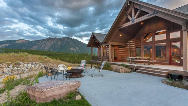Una cabaña con un patio, mobiliario exterior y vistas a las montañas.
