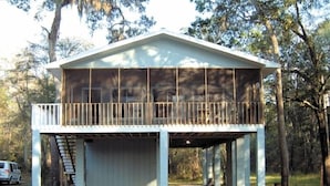 Un immeuble de deux étages doté d’un balcon, entouré d’arbres.