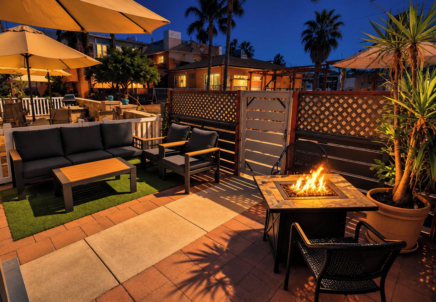 An outdoor patio area with a fire pit, seating, and umbrellas.