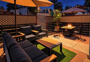 Une terrasse extérieure avec des sièges, un foyer et une clôture décorative.