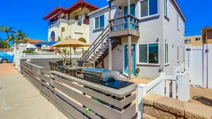 A two-story house with a balcony, a staircase, and a patio area with outdoor furniture. - Renovated Bay Side Condo - 812 (San Diego)