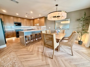 Une cuisine moderne avec des meubles en bois, un îlot central et un coin repas doté de chaises en osier.