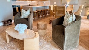 Un salon moderne avec deux canapés, une table basse et un coin repas avec des chaises.